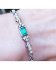 An emerald-cut Muzo Colombian emerald bracelet natural diamonds 14k white gold on a wrist.