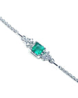 14K white gold bracelet with a central emerald-cut Colombian emerald and diamond accents.