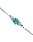 14K white gold bracelet with a central emerald-cut Colombian emerald and diamond accents.