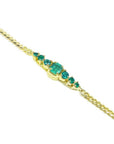 Women's 14K yellow gold bracelet with a central emerald-cut Colombian emerald and smaller round emeralds.