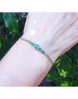 Women's 14K yellow gold bracelet with sparkling medium deep green Colombian emeralds on a wrist.