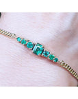Lady’s bracelet featuring natural Colombian emeralds set in 14K yellow gold, showcasing sparkling medium deep green stones from the renowned Muzo mine.