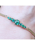 Lady’s bracelet featuring natural Colombian emeralds set in 14K yellow gold, showcasing sparkling medium deep green stones from the renowned Muzo mine.