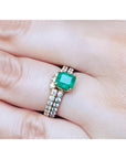 1.39 carat emerald bridal ring set with matching diamond band in 14K gold on a finger.