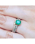 1.39 carat emerald bridal ring set with matching diamond band in 14K gold on a finger.