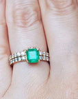A natural emerald bridal ring with matching band set on a person's finger.