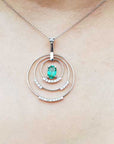 Necklace with a pendant featuring an emerald stone and small diamonds on a person's neck.