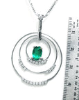 A triple circle of life natural emerald pendant next to a ruler for scale on a white background.