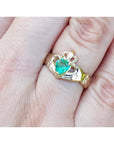 14K yellow gold Claddagh ring with a pear-shaped, medium-green emerald on a finger.