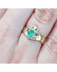 14K yellow gold Claddagh ring with a pear-shaped, medium-green emerald on a finger.