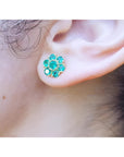 Close-up of an ear wearing a natural emerald cluster earring.