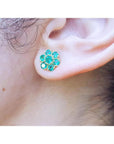 Close-up of an ear wearing a natural emerald cluster earring.