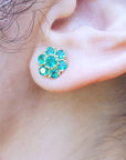 Close-up of an ear wearing an emerald cluster earring.