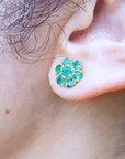 Close-up of an ear wearing an emerald cluster earring.