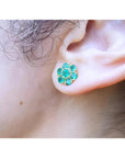 18K yellow gold stud earring with six round-cut natural Colombian emerald petals, worn on an ear.