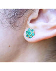 18K yellow gold stud earring with six round-cut natural Colombian emerald petals, worn on an ear.
