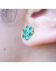 Colombian emerald cluster stud earring with six round-cut petals in 18K yellow gold on an ear.