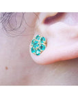 Colombian emerald cluster stud earring with six round-cut petals in 18K yellow gold on an ear.