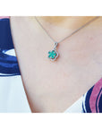 Emerald cluster necklace with diamonds in 14K white gold, clover-like design on a woman's neck.