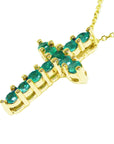 Gold cross pendant with emerald stones on a side position top and gallery are visibles.