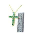14K yellow gold cross pendant necklace with eleven round-cut Colombian emeralds, shown with a ruler for size.