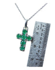 Cross-shaped pendant with round cut natural colombian emeralds on a chain, next to a ruler for scale.