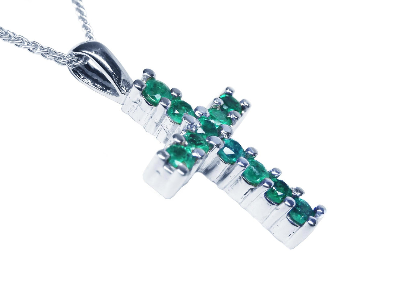 An emerald cross pendant necklace with round cut Colombian emeralds, set in 18k white gold.