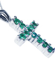 An emerald cross pendant necklace with round cut Colombian emeralds, set in 18k white gold.