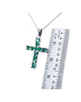 Round-cut emerald cross pendant necklace in 18K white gold, shown with a ruler for size.