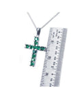 Round-cut emerald cross pendant necklace in 18K white gold, shown with a ruler for size.