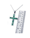 Round-cut emerald cross pendant necklace in 18K white gold, shown with a ruler for size.