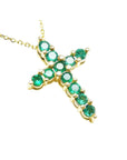 A cross pendant on a right-side position and top view of eleven round cut emeralds prong set in yellow gold