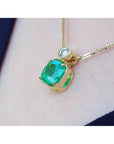 A yellow gold necklace with a cushion emerald pendant on a skin background