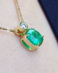 Gold necklace with a natural emerald pendant on a soft fabric background