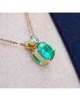 Gold necklace with a natural emerald pendant on a soft fabric background