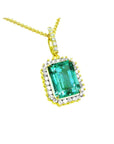 the topside view of a natural colombian emerald pendant emerald-cut surrounded by a halo diamond in 18k yellow gold.