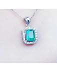 Emerald-cut emerald pendant with halo diamonds in 14K white gold on a delicate chain.