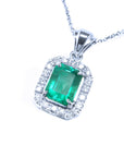 Emerald green gemstone pendant with diamond accents on a left-side position topside view.