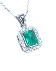 A natural emerald-cut gemstone emerald pendant with a halo diamond accent on a topside view position.