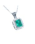 A natural emerald-cut gemstone emerald pendant with a halo diamond accent on a topside view position.