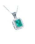 A natural emerald-cut gemstone emerald pendant with a halo diamond accent on a topside view position.