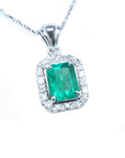 Emerald-cut emerald gemstone pendant with diamond accents on a topside view position.
