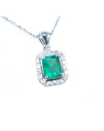 Emerald-cut emerald pendant with halo diamonds in 14K white gold on a delicate chain.