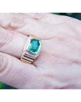Men's 18K yellow gold ring with a bezel-set emerald-cut green emerald and small accent diamonds.