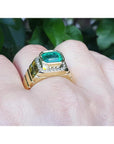 Men's 18K yellow gold ring with a bezel-set emerald-cut green emerald and diamond accents.