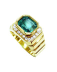 Men's 18K yellow gold ring with a bezel-set emerald-cut green emerald and diamond accents.