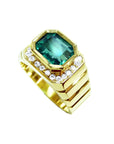 Men's 18K yellow gold ring with a bezel-set emerald-cut green emerald and diamond accents.