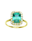 A rectangular emerald encircled into a halo natural diamond ring in 14k yellow gold.