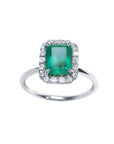 Emerald-cut Muzo emerald ring with halo diamonds in 14K white gold.