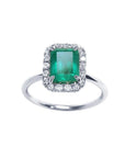 Emerald-cut Muzo emerald ring with halo diamonds in 14K white gold.